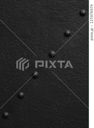 Textured black metal surface with rivets creating a minimalist and bold aesthetic in a contemporary design setting. 125976974