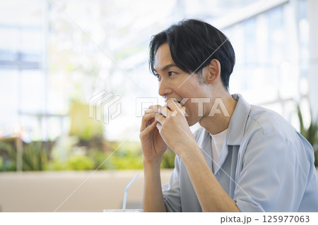 ハンバーガーを食べる若い男性　横顔 125977063