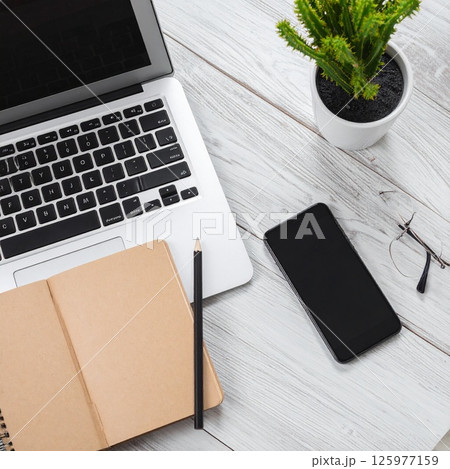 ノートパソコンとスマートフォンを並べたデスク上でのリモートワーク風景 125977159