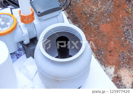 Installation process shows filtration system component ready for connection in swimming pool backyard setting. Installation process shows filtration system component ready for connection in swimming pool backyard setting. 125977420