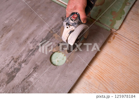 Skilled hands cut granite tiles during repair work in a home workshop in daylight Skilled hands cut granite tiles during repair work in a home workshop in daylight 125978184