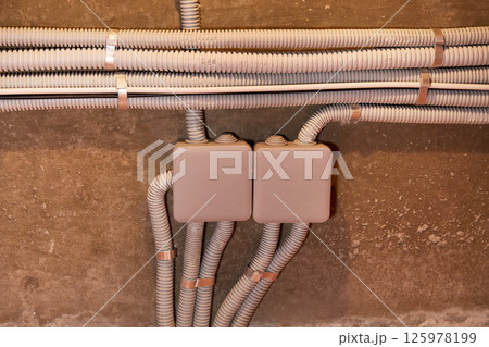 The electrical wires in the protective corrugated cable tube and the junction box are neatly laid on the ceiling 125978199