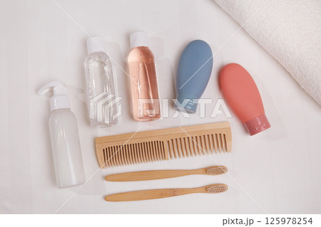 A travel set of toiletries is neatly laid out on a white surface. It includes essential personal hygiene items in bottles A travel set of toiletries is neatly laid out on a white surface. It includes essential personal hygiene items in bottles 125978254