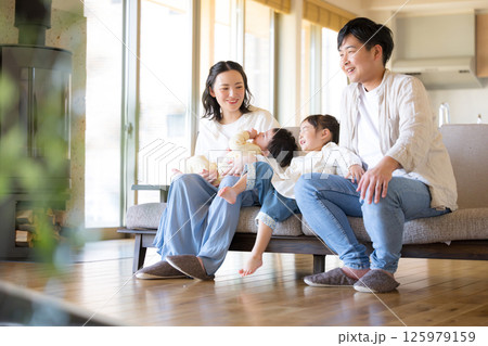 木のぬくもりのある新築のような家の自宅のソファーでくつろぐ4人の日本人家族 木のぬくもりのある新築のような家の自宅のソファーでくつろぐ4人の日本人家族 125979159