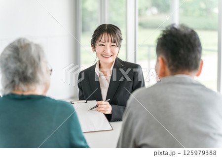 高齢者夫婦に説明・提案・案内・おすすめするビジネスウーマン 125979388