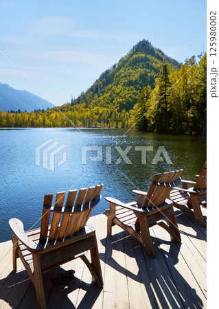Beautiful autumn landscape. Wooden deck chairs on the lake shore. Beautiful autumn landscape. Wooden deck chairs on the lake shore. 125980002
