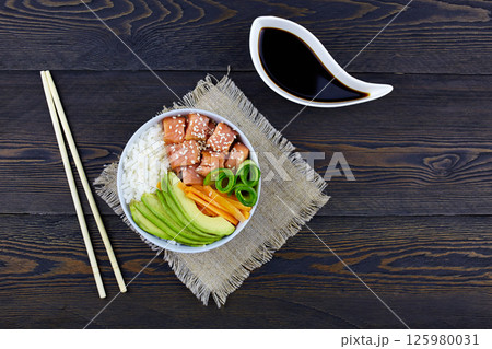 Hawaiian salmon fish poke bowl with rice, avocado, cucumber, carrot, soy sauce Hawaiian salmon fish poke bowl with rice, avocado, cucumber, carrot, soy sauce 125980031