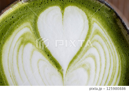 Full frame shot of latte art on Matcha latte surface. A matcha latte consists of matcha powder, water, and milk. Full frame shot of latte art on Matcha latte surface. A matcha latte consists of matcha powder, water, and milk. 125980886