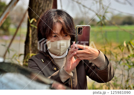 携帯電話のカメラで写真を撮る女性 携帯電話のカメラで写真を撮る女性 125981090