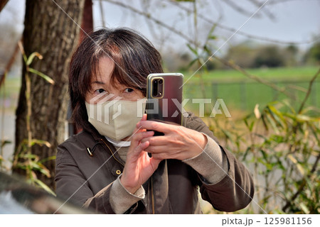 携帯電話のカメラで写真を撮る女性 125981156