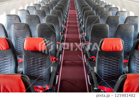 Empty interior of cabin of airplane with rows of black and red seats, High angle view 125981482
