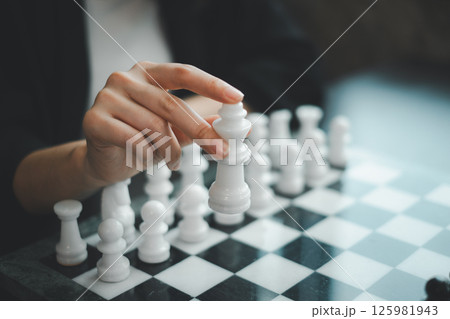 A close-up image of a hand holding a white chess piece, poised over a chessboard, symbolizing strategy and decision-making. A close-up image of a hand holding a white chess piece, poised over a chessboard, symbolizing strategy and decision-making. 125981943
