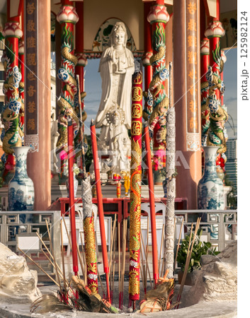 Large statue of Guanyin in colorful temple with dragon columns during sunny afternoon. Sriracha, Thailand. Large statue of Guanyin in colorful temple with dragon columns during sunny afternoon. Sriracha, Thailand. 125982124