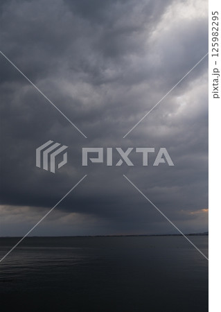 厚い雲に覆われた春の海 125982295