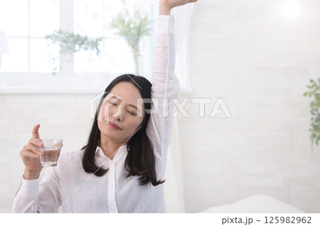 リビングで水を飲むミドル女性 リビングで水を飲むミドル女性 125982962