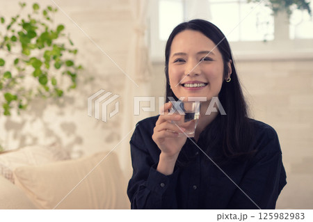リビングで水を飲むミドル女性 125982983