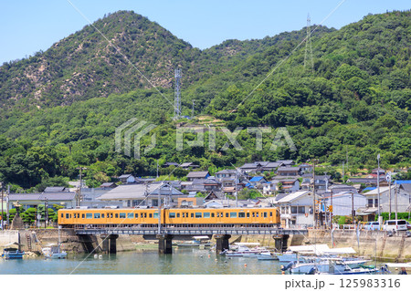 黒滝山を背景に黄色い車両の呉線が忠海港を通る 黒滝山を背景に黄色い車両の呉線が忠海港を通る 125983316