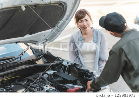 自動車のエンジンルームでドライバーに説明する整備士の男性スタッフ 125983973