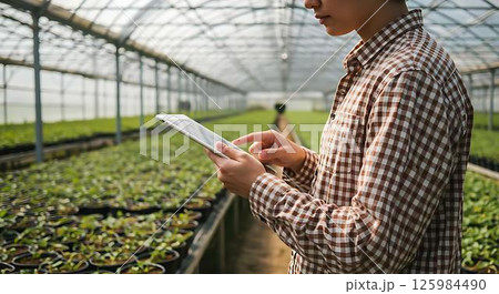 Farmer using tablet in greenhouse 125984490