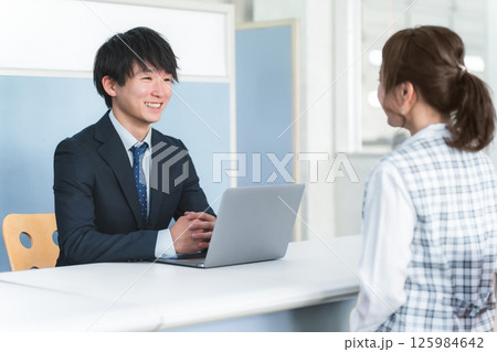 受付・窓口で女性客を接客する若いアジア人ビジネスマン 125984642