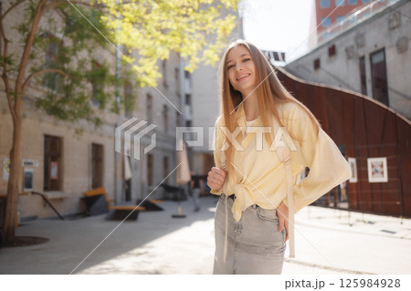 Young woman smiling in a sunlit urban courtyard while enjoying a casual day out in the city during spring Young woman smiling in a sunlit urban courtyard while enjoying a casual day out in the city during spring 125984928