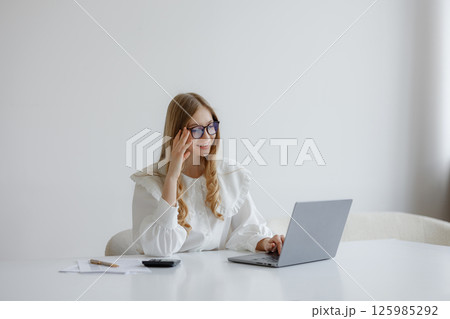 Young woman working on laptop in modern office with minimalistic design Young woman working on laptop in modern office with minimalistic design 125985292