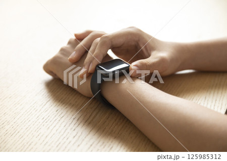 business, technology and people concept - close up of male hand wearing watch at wooden table business, technology and people concept - close up of male hand wearing watch at wooden table 125985312