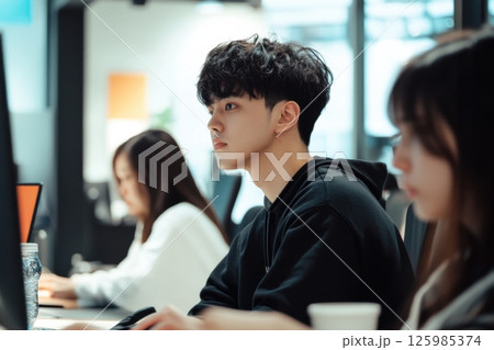 Students engaged in focused study session at a modern coworking space during daytime hours 125985374