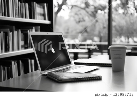 Working on a laptop in a quiet library with coffee and notebooks during a peaceful afternoon Working on a laptop in a quiet library with coffee and notebooks during a peaceful afternoon 125985715