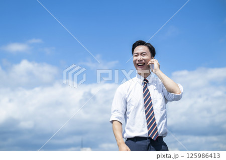 ビジネスマン 電話 スマホ 青空 笑顔 ビジネスマン 電話 スマホ 青空 笑顔 125986413