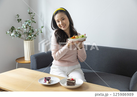 healthy eating, dieting and people concept - close up of young woman eating vegetable salad at home 125986989