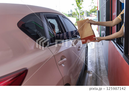 Hand Man in car receiving coffee in drive thru fast food restaurant. Hand Man in car receiving coffee in drive thru fast food restaurant. 125987142