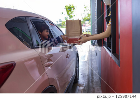 Hand Man in car receiving coffee in drive thru fast food restaurant. 125987144