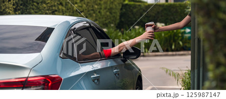 Hand Man in car receiving coffee in drive thru fast food restaurant. Hand Man in car receiving coffee in drive thru fast food restaurant. 125987147