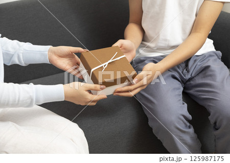Valentine Gift. Happy Young Couple with Valentine's Day Present isolated on a White background. Happy Man giving a gift to his Girlfriend. Holiday 125987175