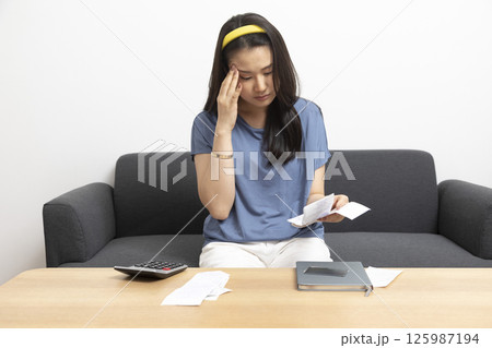 beautiful sad woman at home living room couch calculating monthly expenses worried in stress with bank papers and documents in paying taxes mortgage debt and cost of living concept 125987194