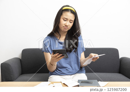 beautiful sad woman at home living room couch calculating monthly expenses worried in stress with bank papers and documents in paying taxes mortgage debt and cost of living concept beautiful sad woman at home living room couch calculating monthly expenses worried in stress with bank papers and documents in paying taxes mortgage debt and cost of living concept 125987200