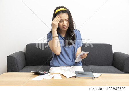beautiful sad woman at home living room couch calculating monthly expenses worried in stress with bank papers and documents in paying taxes mortgage debt and cost of living concept beautiful sad woman at home living room couch calculating monthly expenses worried in stress with bank papers and documents in paying taxes mortgage debt and cost of living concept 125987202