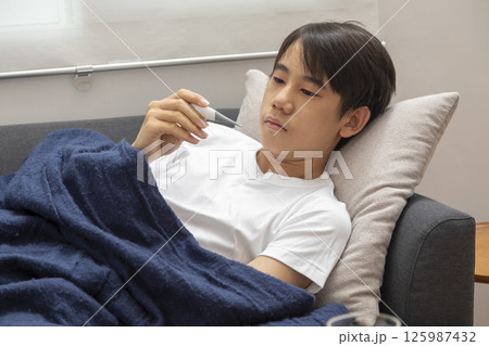 Little asian sick boy sitting on sofa Little asian sick boy sitting on sofa 125987432