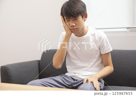 Little boy suffering from headache while lying in bed at home 125987655