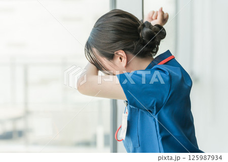 病院の窓を叩いて悔しがる医師・医者・看護師・医療従事者・技師の女性 125987934