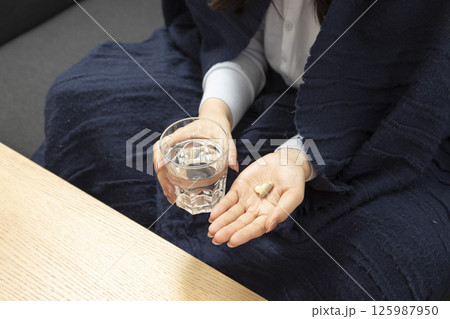 Healthcare treatment supplements. Handful of white round pills in female patients palm woman arm holding heap of small round meds and glass of water before taking medication Healthcare treatment supplements. Handful of white round pills in female patients palm woman arm holding heap of small round meds and glass of water before taking medication 125987950