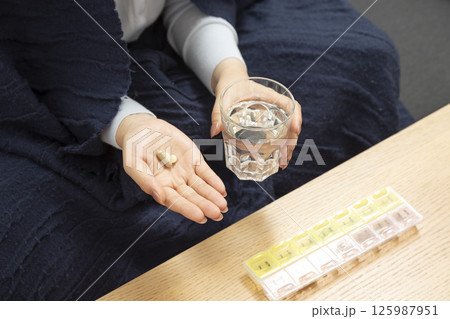 Healthcare treatment supplements. Handful of white round pills in female patients palm woman arm holding heap of small round meds and glass of water before taking medication Healthcare treatment supplements. Handful of white round pills in female patients palm woman arm holding heap of small round meds and glass of water before taking medication 125987951