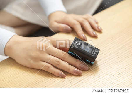 Pulse oximeter on womans left hand. Oxygen level and pulse measuring. Pulse oximeter on womans left hand. Oxygen level and pulse measuring. 125987966
