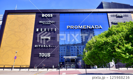 Warsaw, Poland. 1 May 2025. The front wall and the entrance door to the modern shopping center known as the Promenada in sunny day. Warsaw, Poland. 1 May 2025. The front wall and the entrance door to the modern shopping center known as the Promenada in sunny day. 125988216