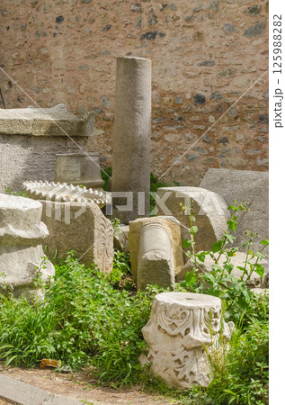 Stone remnants of ancient architecture surrounded by lush green plants and nature. High quality photo 125988282