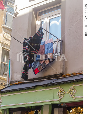 Blankets and towels are hanging on balcony railing drying in sunlight with urban view. High quality photo 125988289
