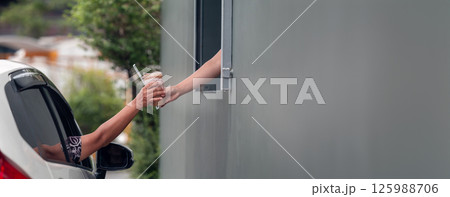 Hand Man in car receiving coffee in drive thru fast food restaurant.  125988706