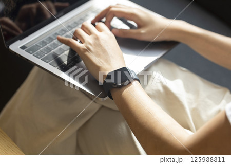 Woman hand with smart watch on wrist, wearable watch and technology computer laptop for communication, checking time. 125988811