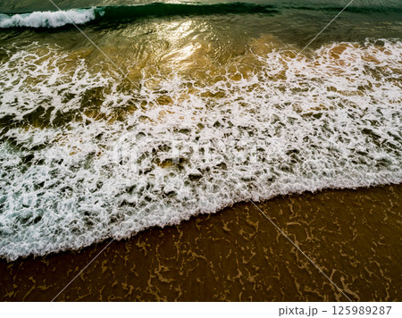 Aerial view Top down Waves crashing on sandy shore,Dark sea surface in summer day background,Seascape top view waves at Phuket Thailand 125989287